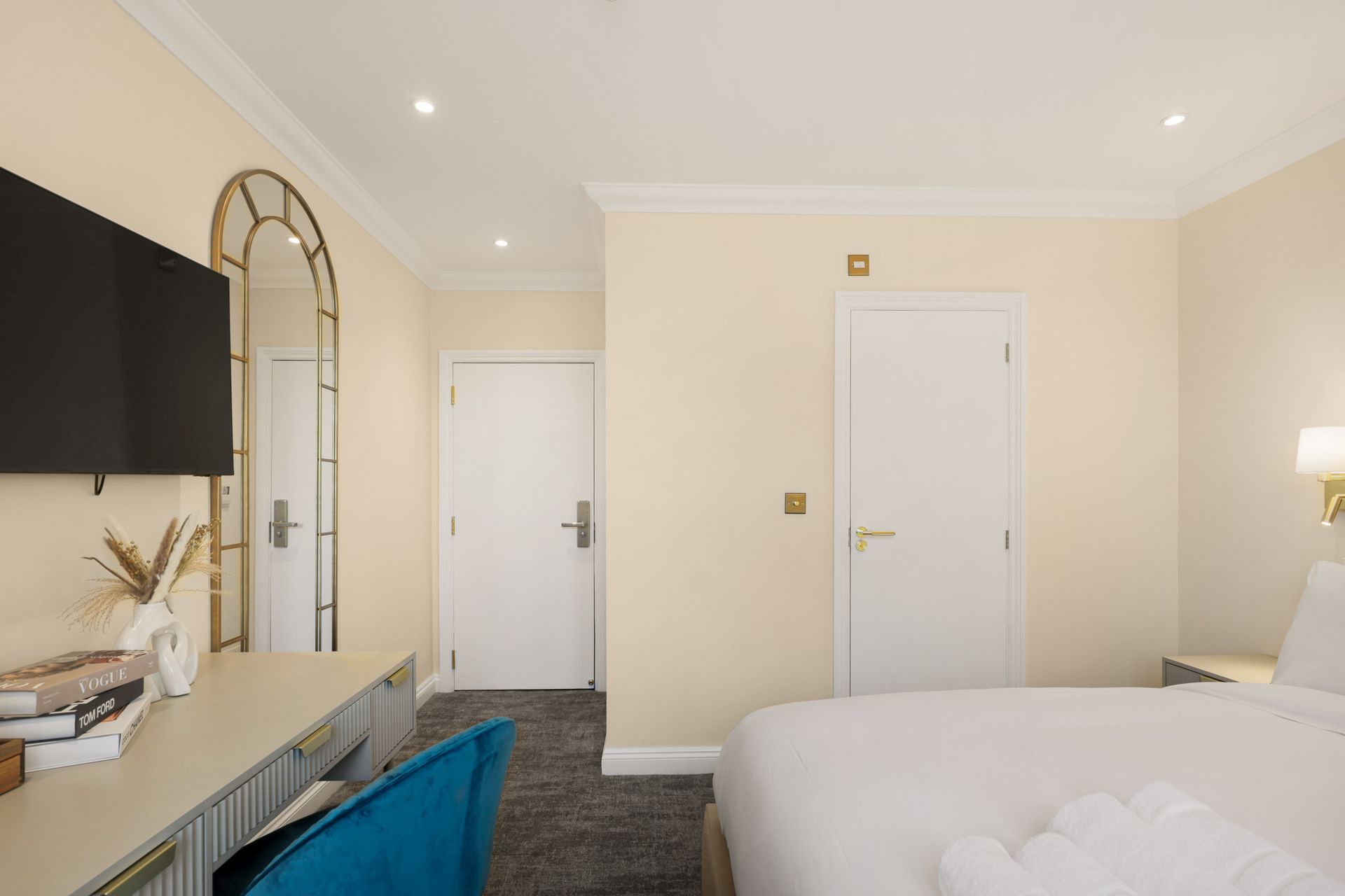 A hotel room with a bed , desk , television and mirror.