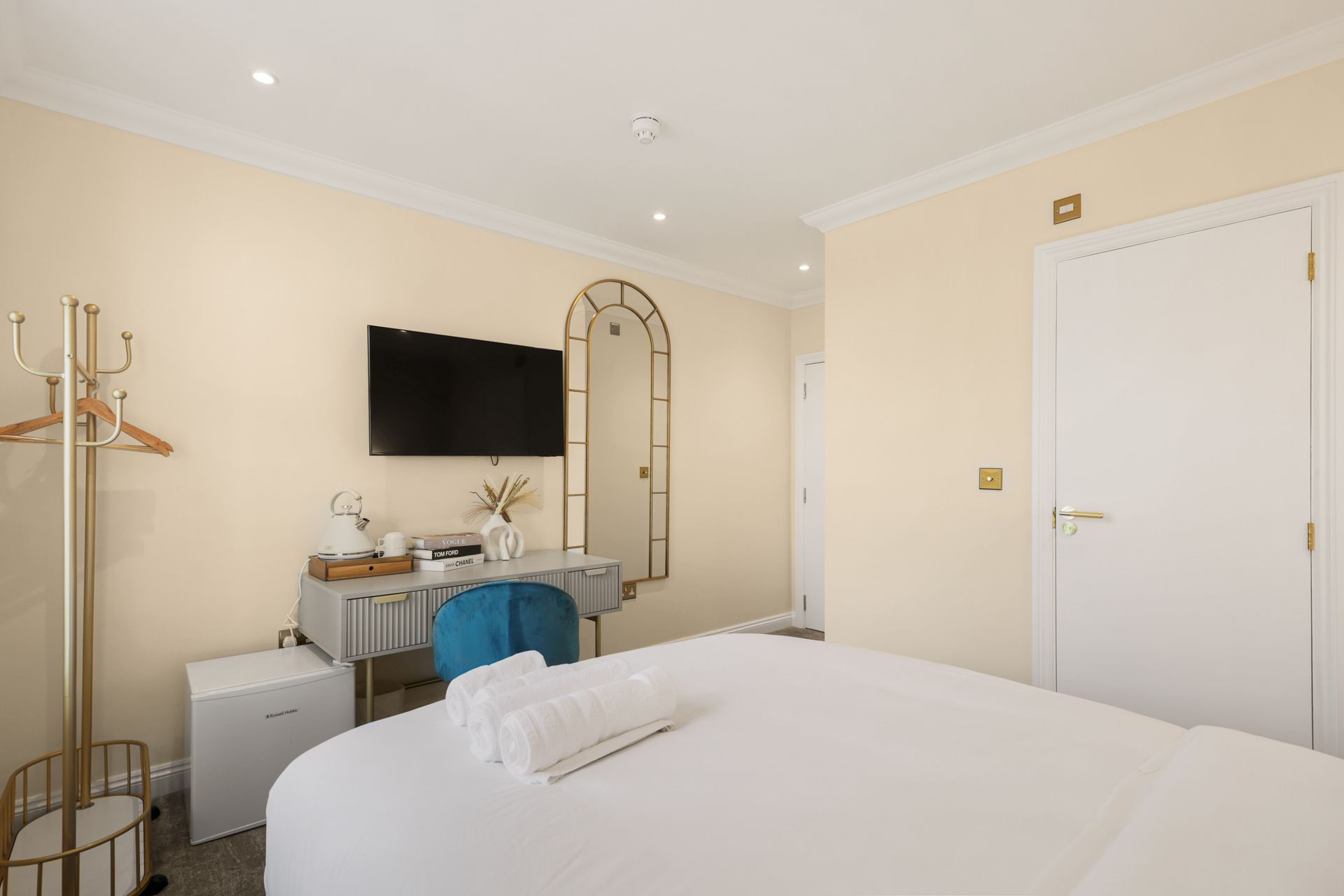 A hotel room with a bed , desk , television and mirror.
