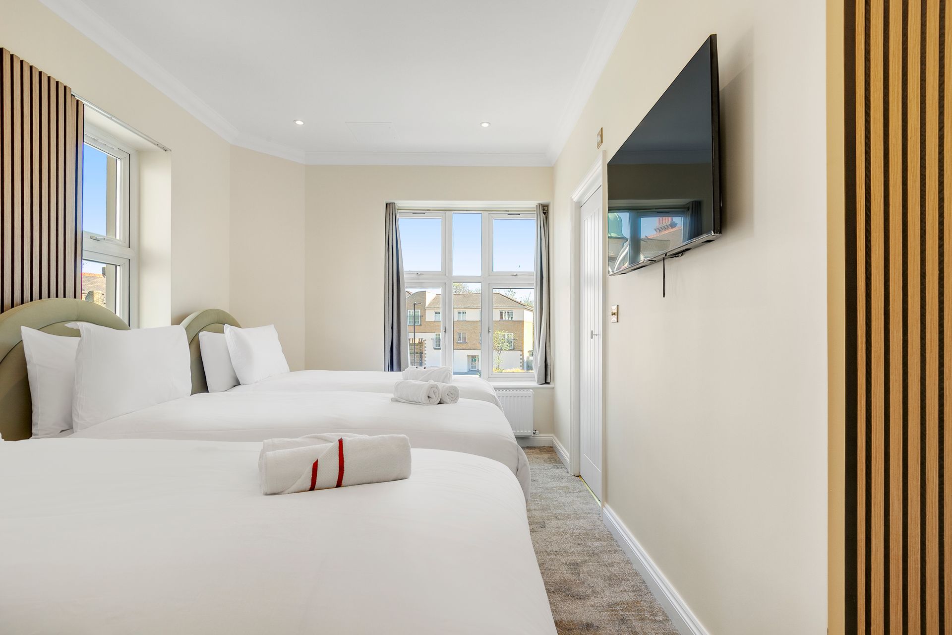 A hotel room with three beds and a flat screen tv.