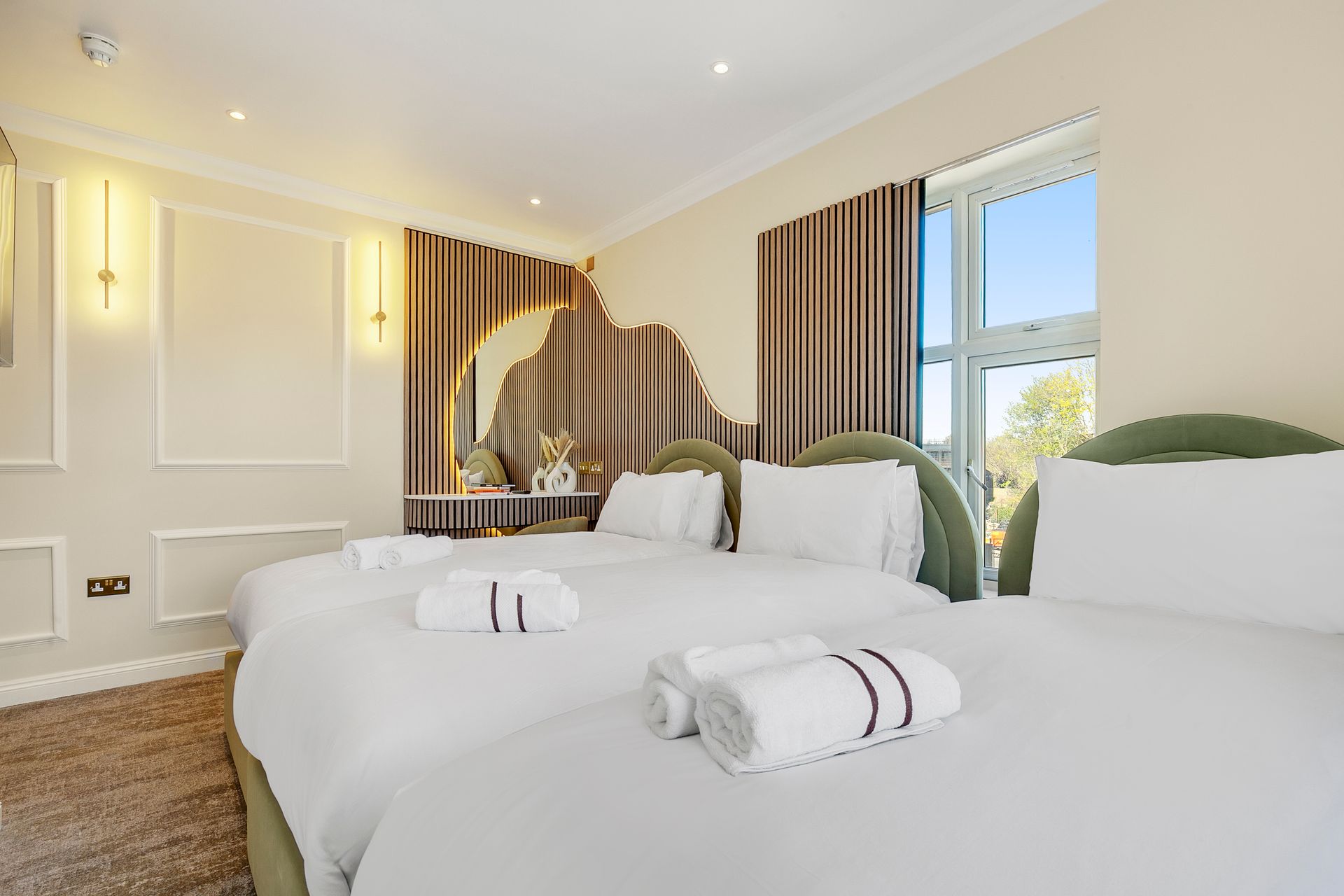 A hotel room with three beds and a large window.