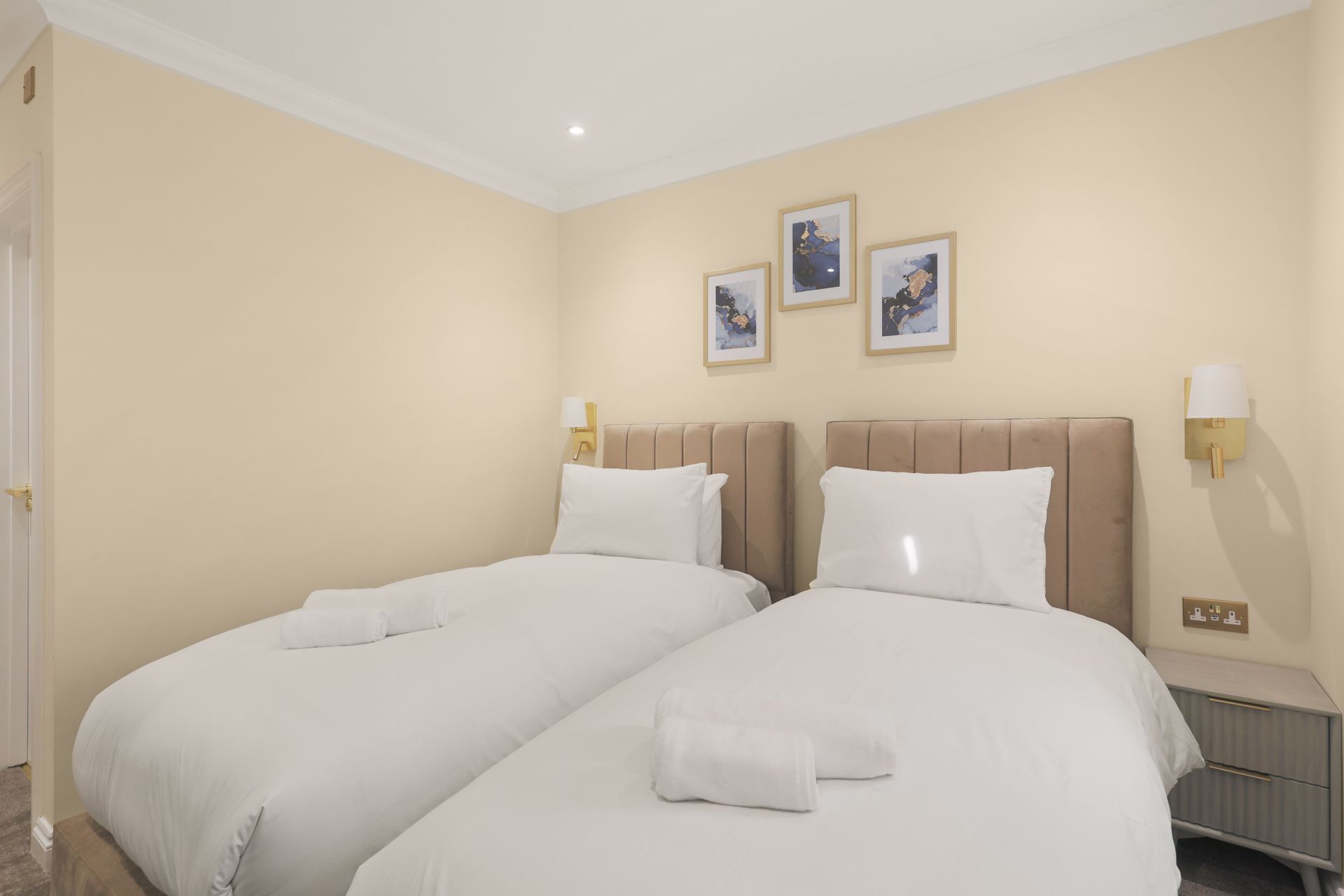 A hotel room with two beds and three pictures on the wall.