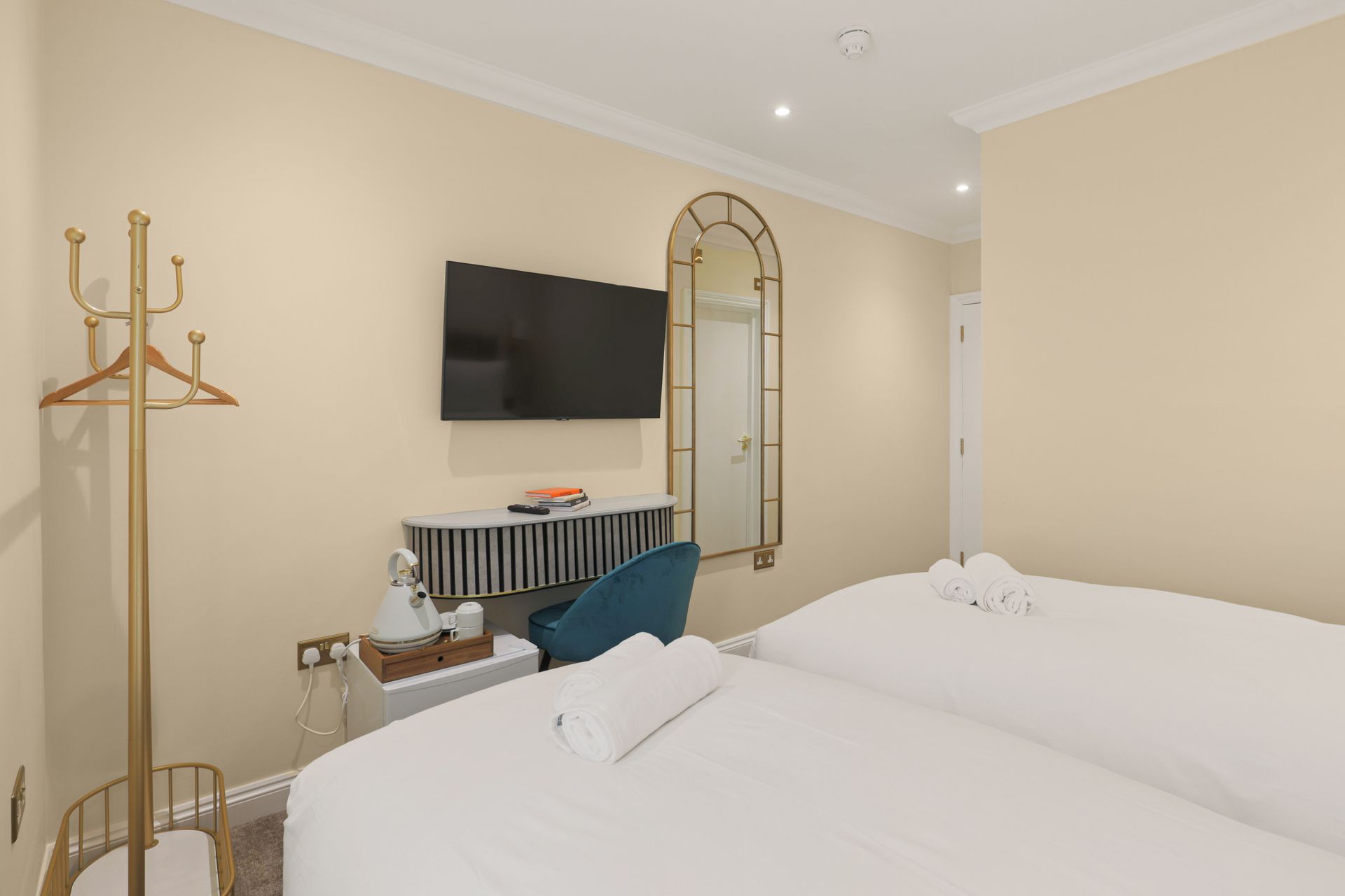 A hotel room with two beds , a desk and a flat screen tv.