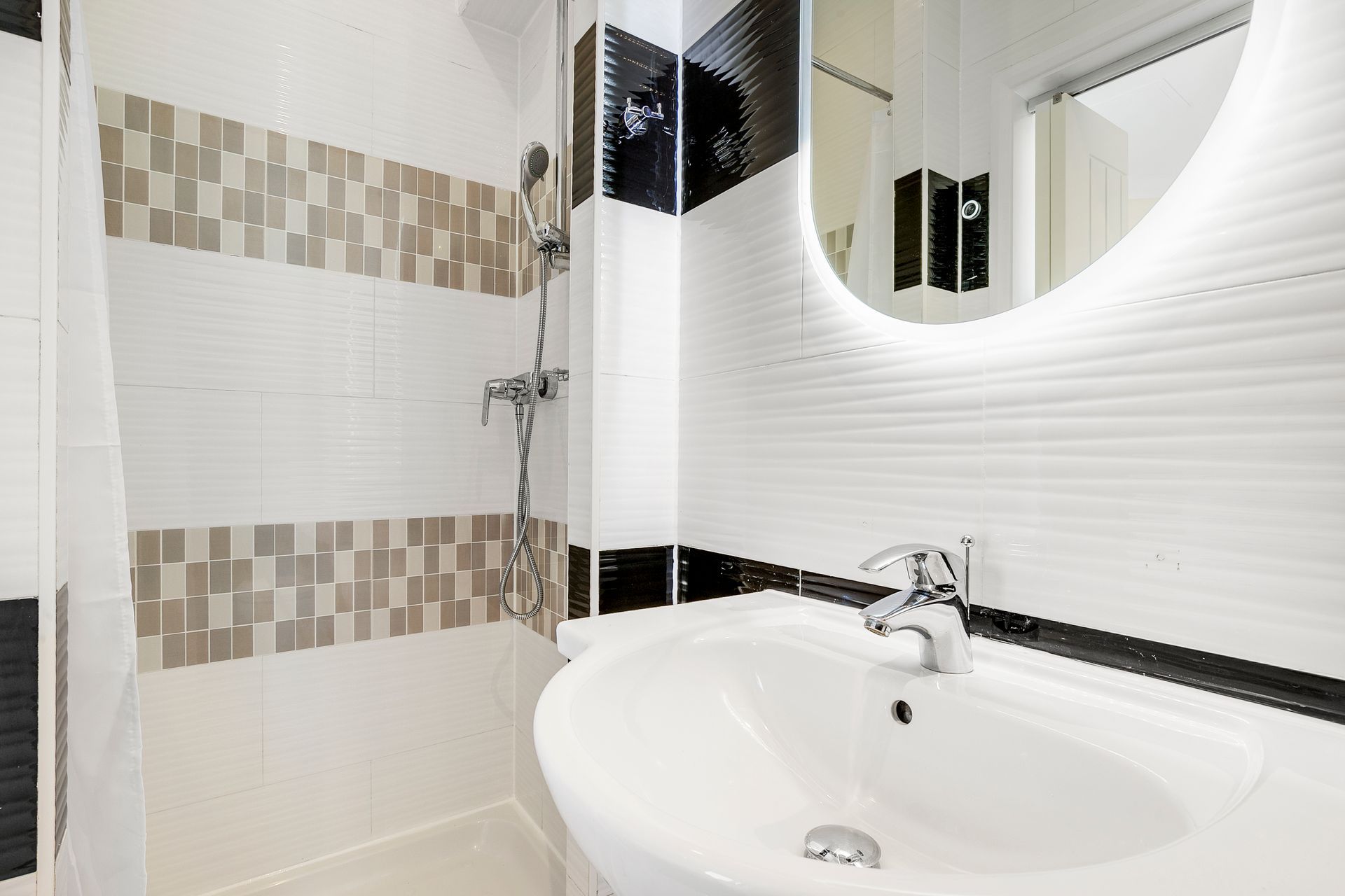 A bathroom with a sink , mirror and shower.