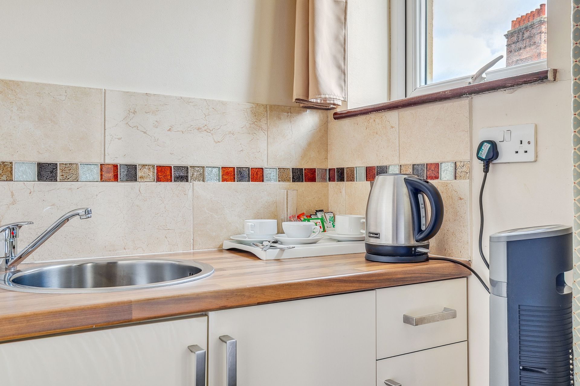 A kitchen with a sink and a kettle on the counter.