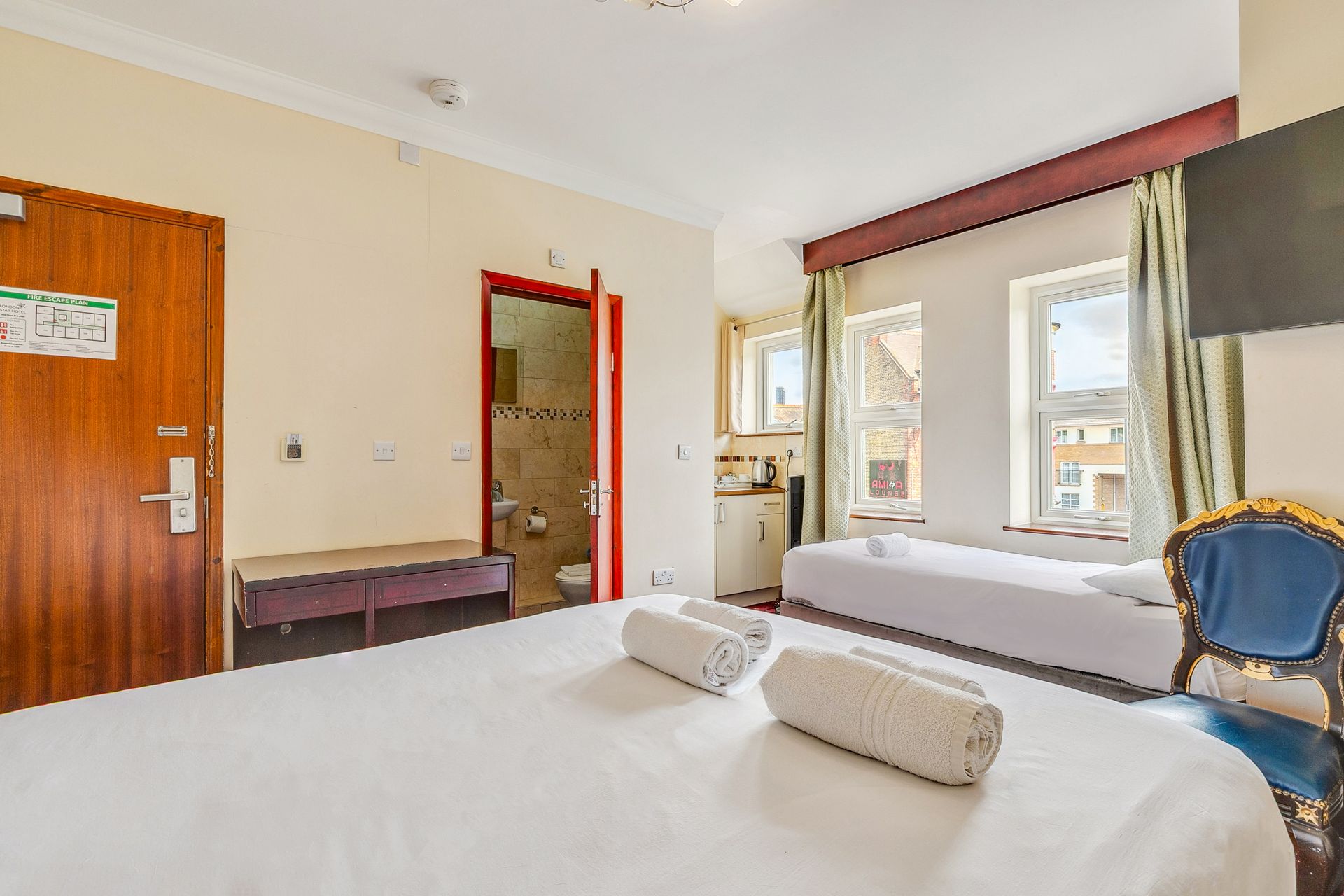 A hotel room with a bed , chair and television.