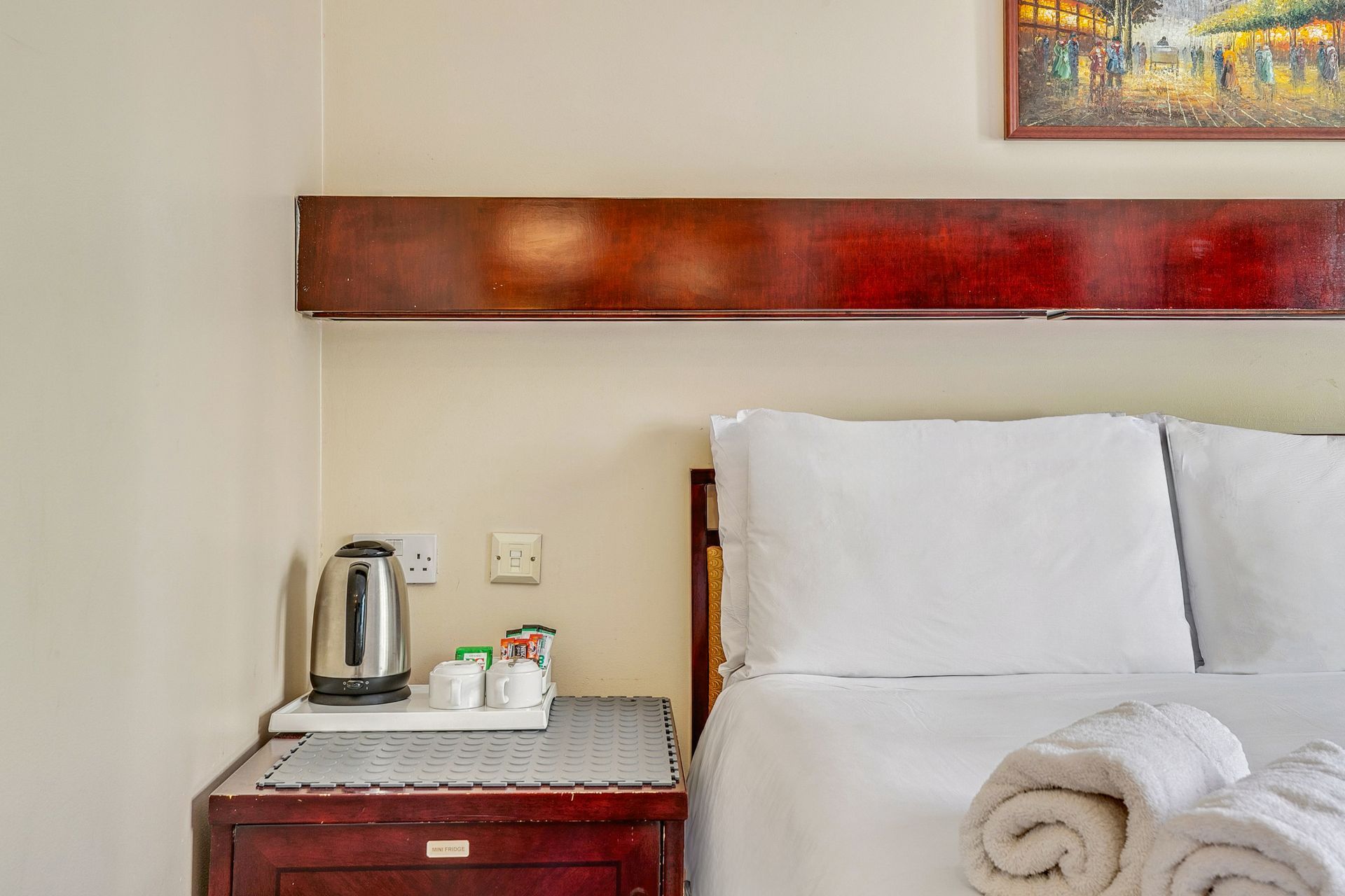 A hotel room with a bed , nightstand , and a painting on the wall.