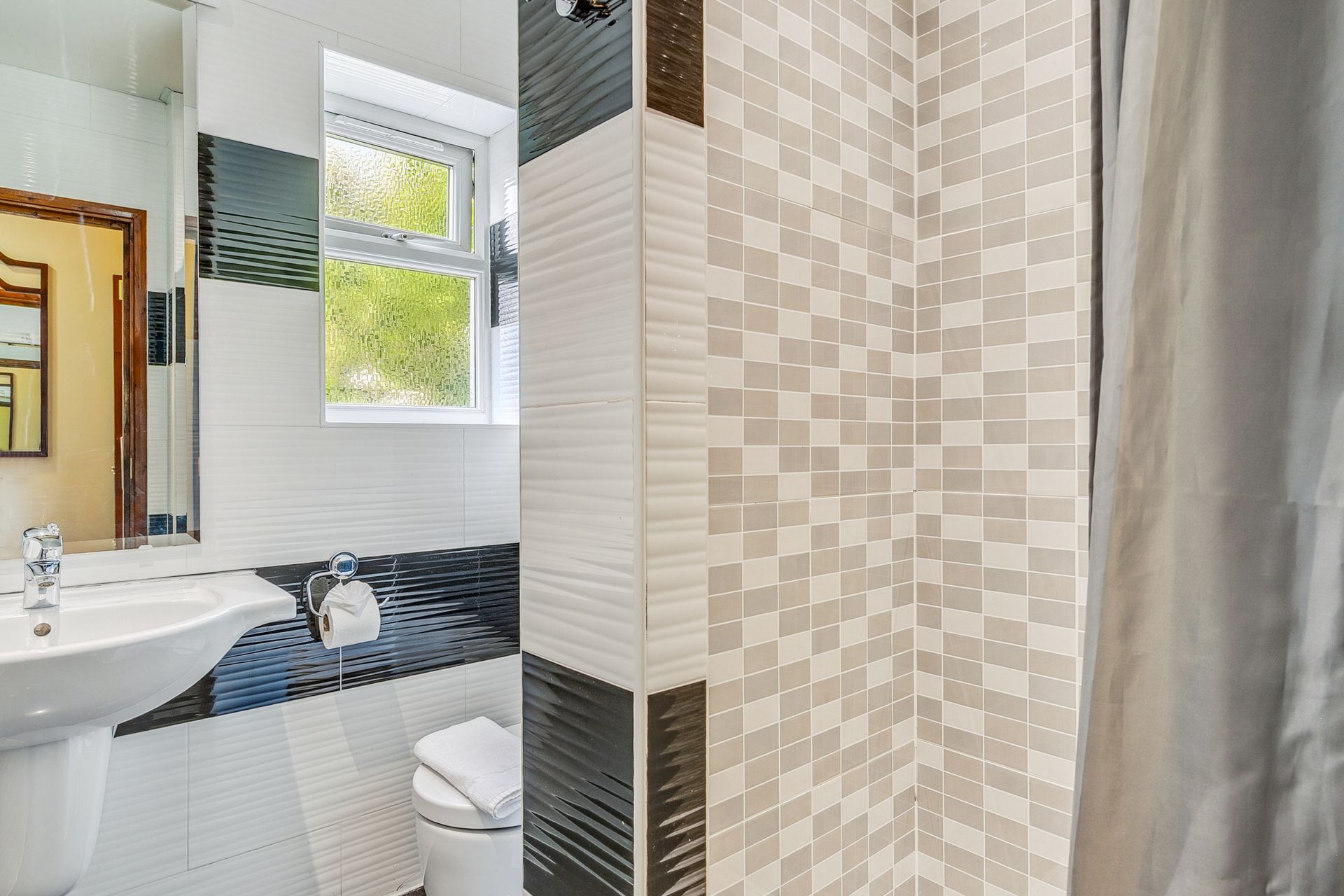 A bathroom with a toilet , sink and shower curtain.