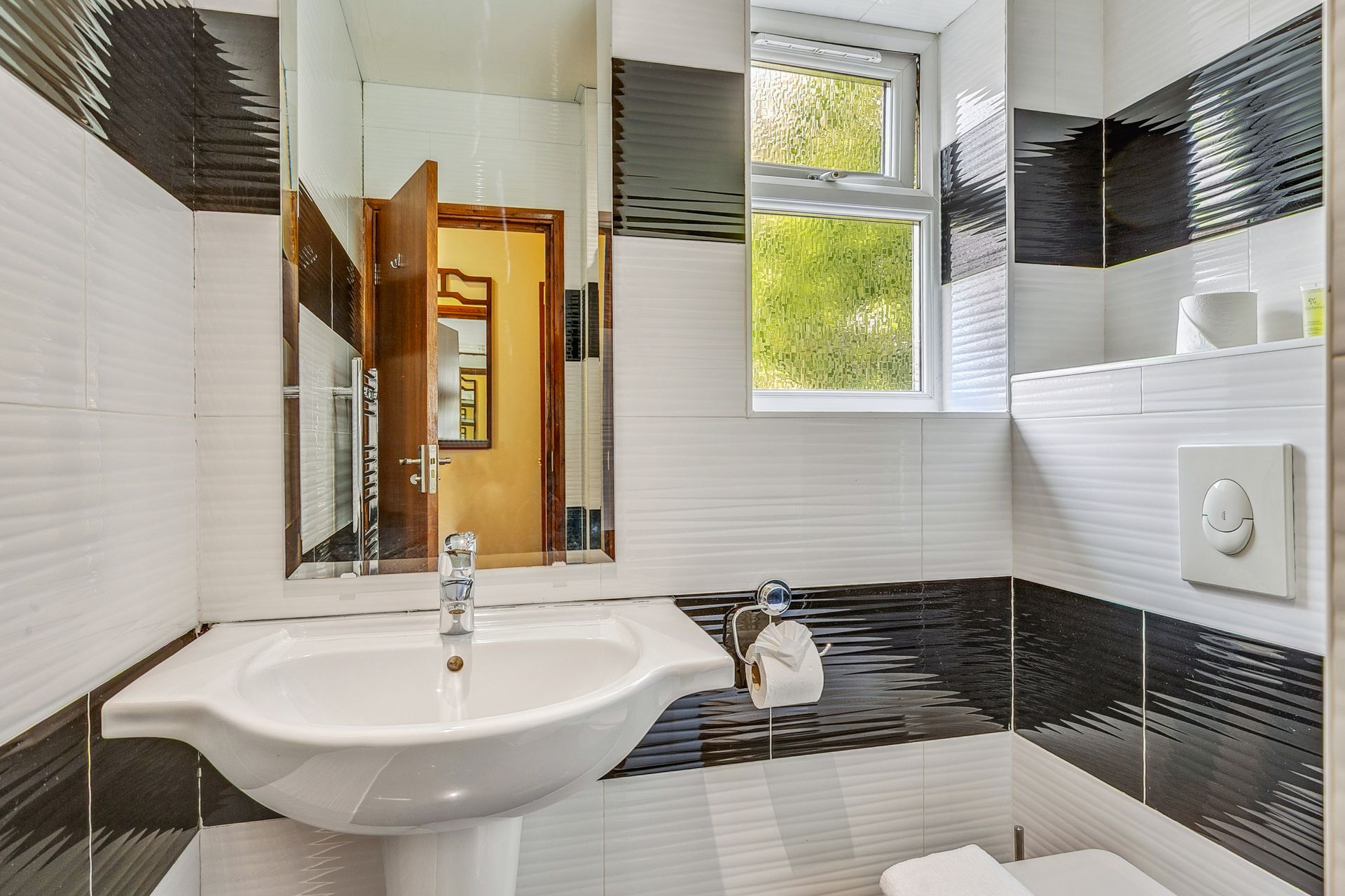 A bathroom with a sink , toilet , mirror and window.