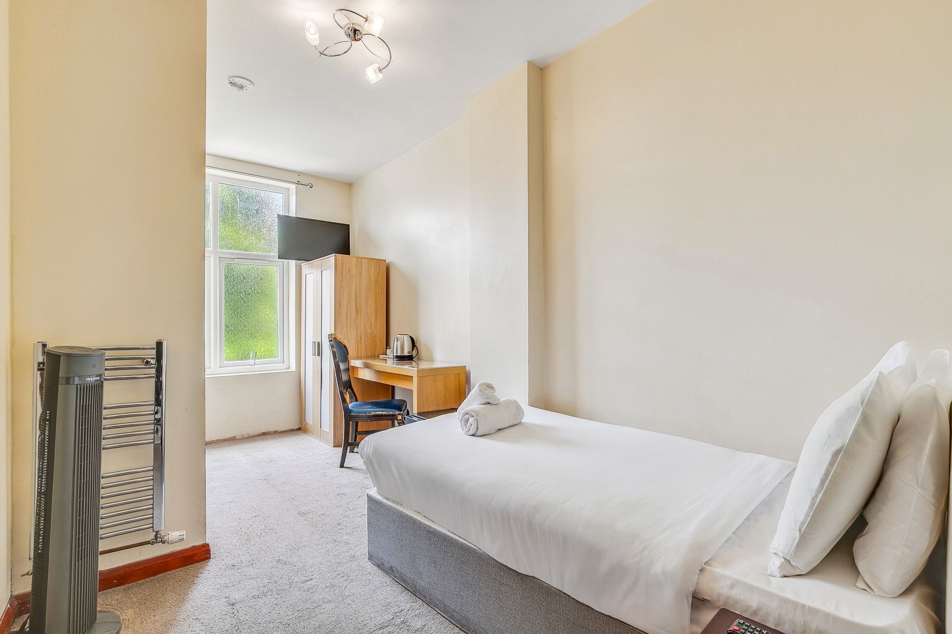 A hotel room with a bed , desk , chair and window.
