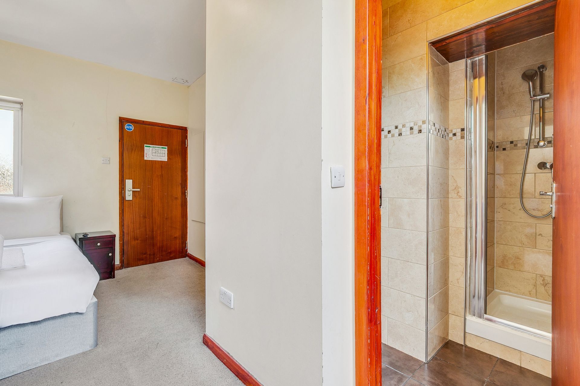 A bedroom with a bed and a walk in shower.