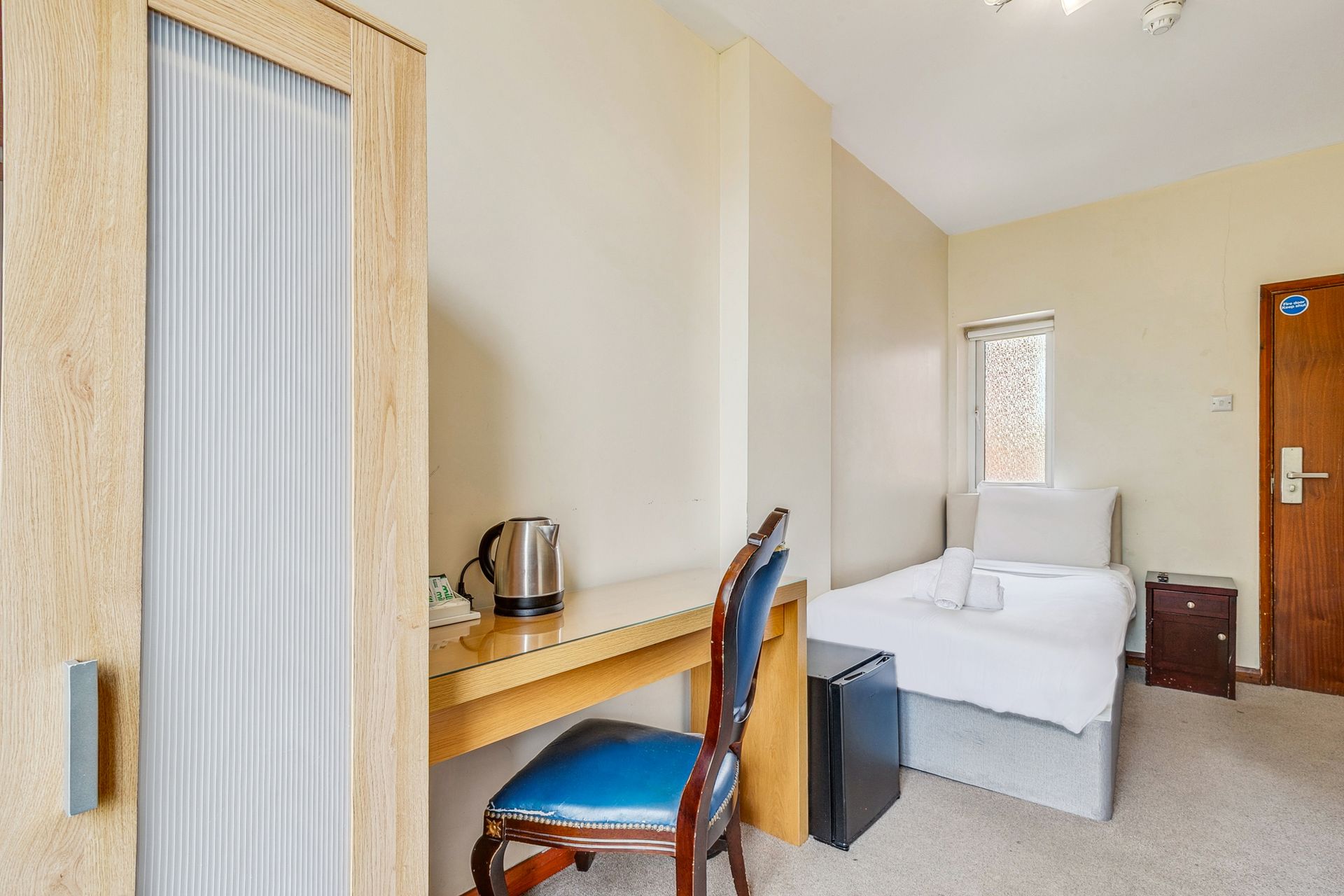 A hotel room with a bed , desk and chair.