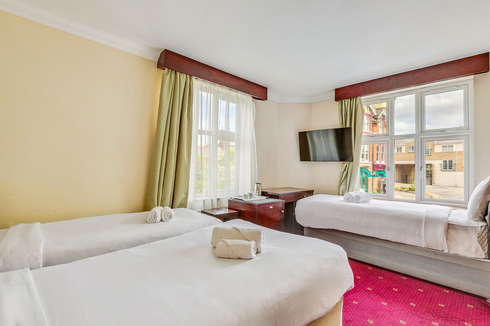 A hotel room with three beds and a flat screen tv.