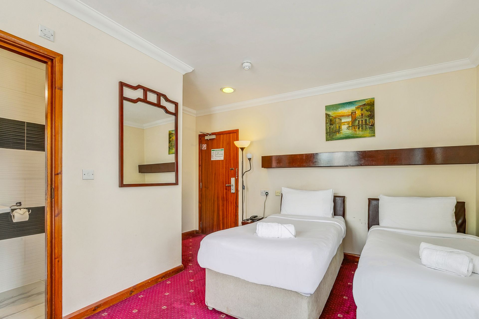 A hotel room with two beds and a mirror.