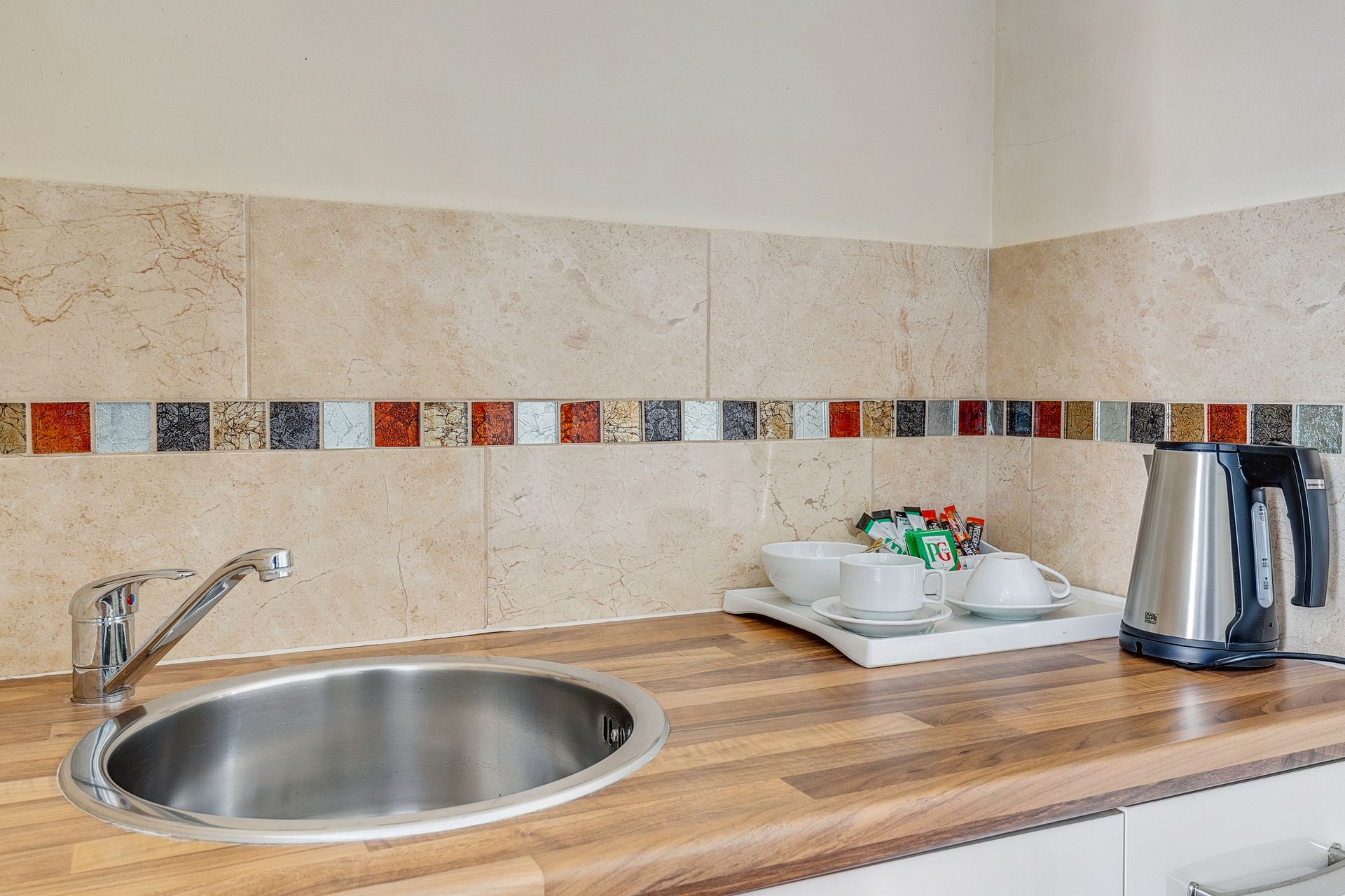 A kitchen counter with a sink and a kettle on it.