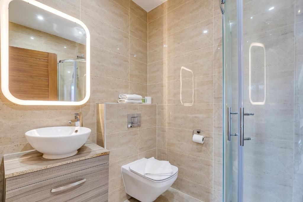 A bathroom with a toilet , sink , mirror and shower stall.