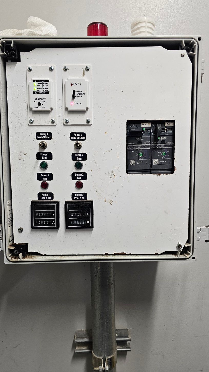 Industrial control panel with switches, indicator lights, and circuit breakers on a wall-mounted metal cabinet