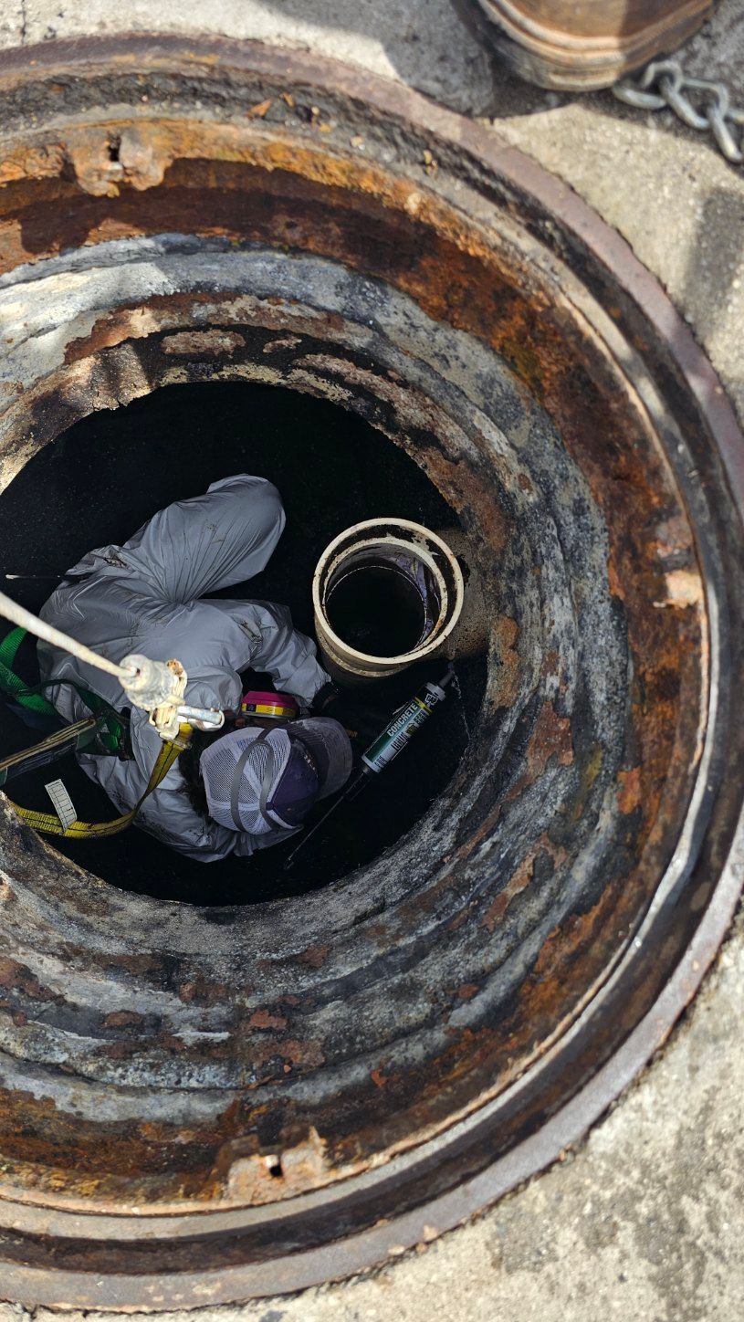 Worker descending into a rusty manhole with ropes and gear