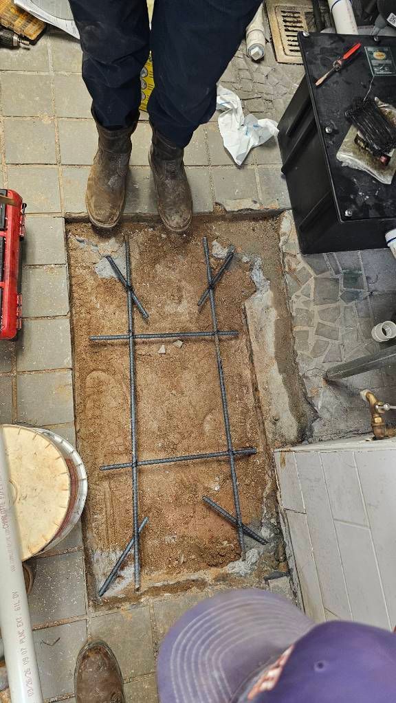 Construction worker standing over a rebar-filled trench in a concrete floor slab