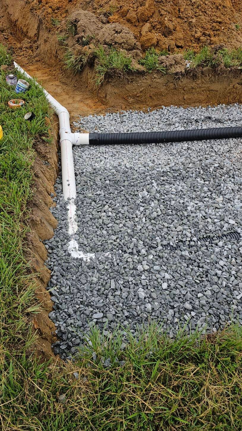 Gravel drainage trench beside grass, lined with white edging and a black pipe in the corner
