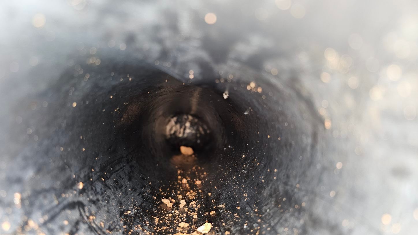 Close-up of a dark tunnel opening with a bright, dusty rim and a small central hole.