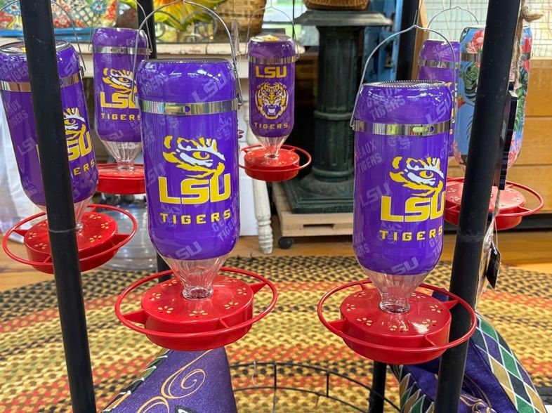 Purple LSU Tigers bottle-style feeders in a store display with red bases and hanging black rails