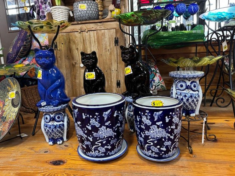 Blue and black cat figurines and patterned planters on a wooden table in a decorative display