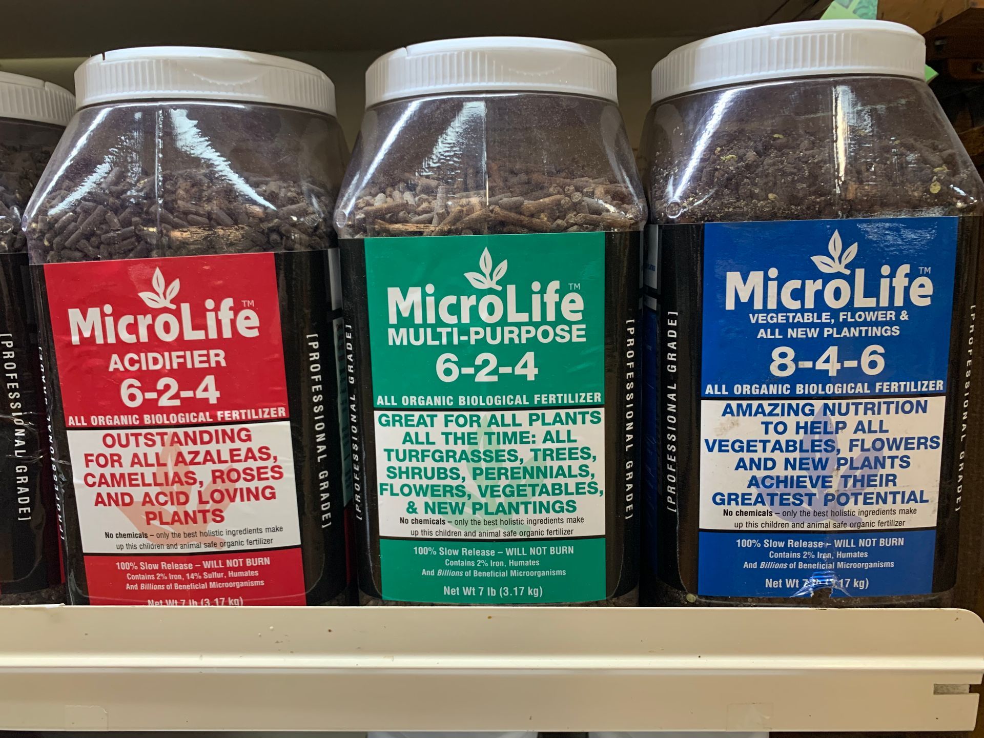 Three Microlife fertilizer jugs on a store shelf, with red, green, and blue labels.