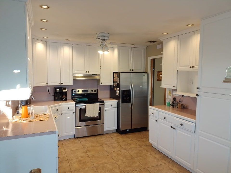 Bright white modern kitchen with stainless steel appliances and tan tile floor