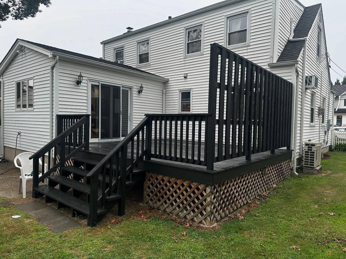 White house with black accessibility ramp and stairs leading to a side entrance