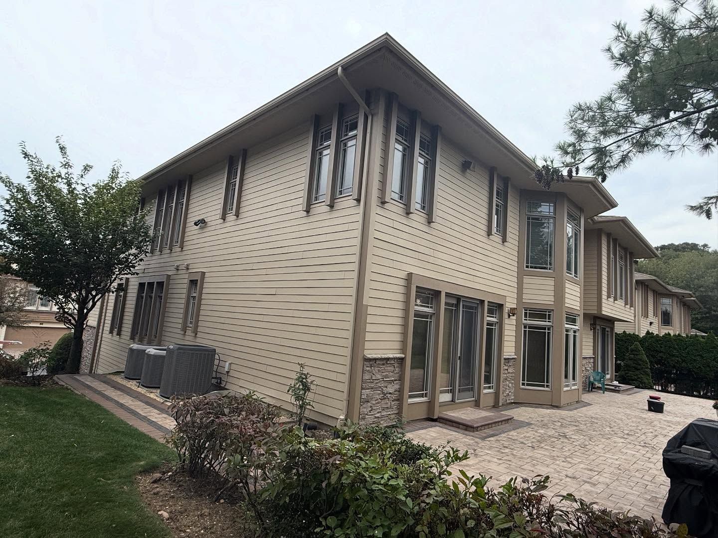 Two-story beige house under construction with exterior siding, windows, and a gravel yard