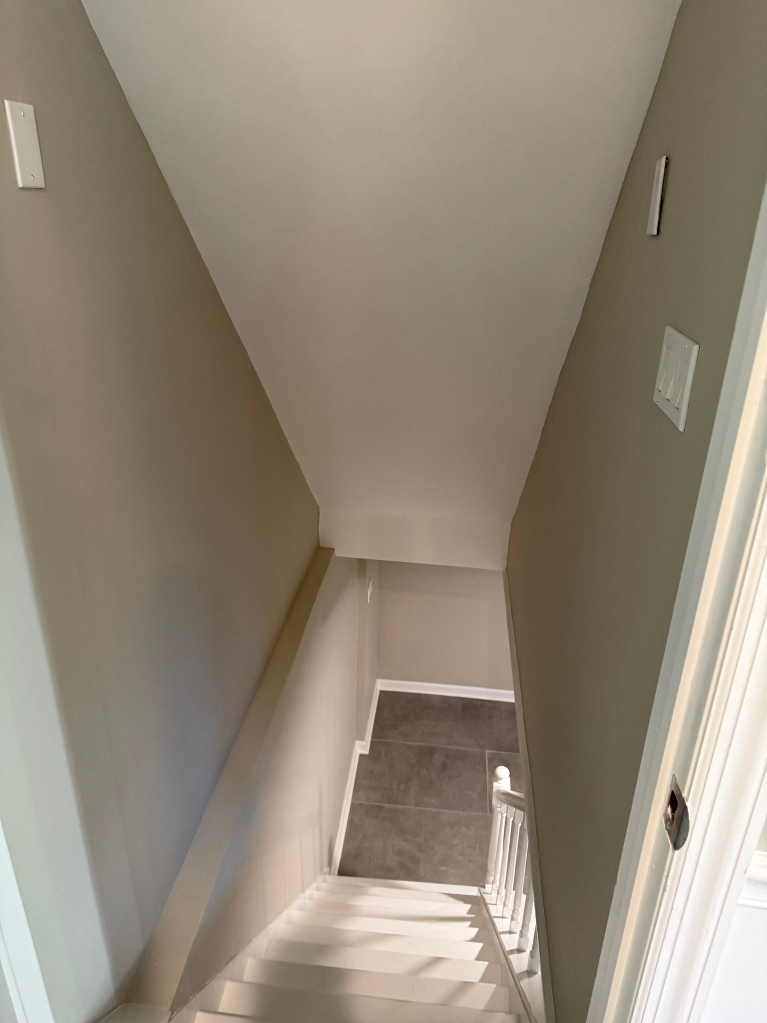 Stairwell with white walls and beige carpet leading down to a lower landing.