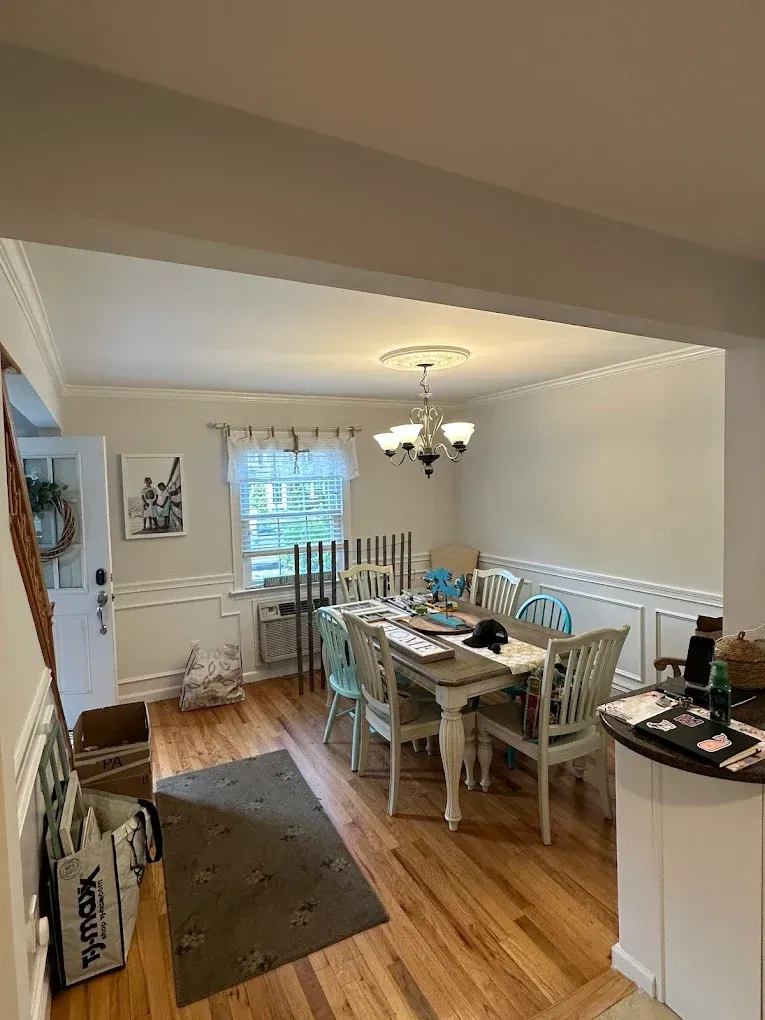 Dining room with white table, turquoise chairs, chandelier, and hardwood floor