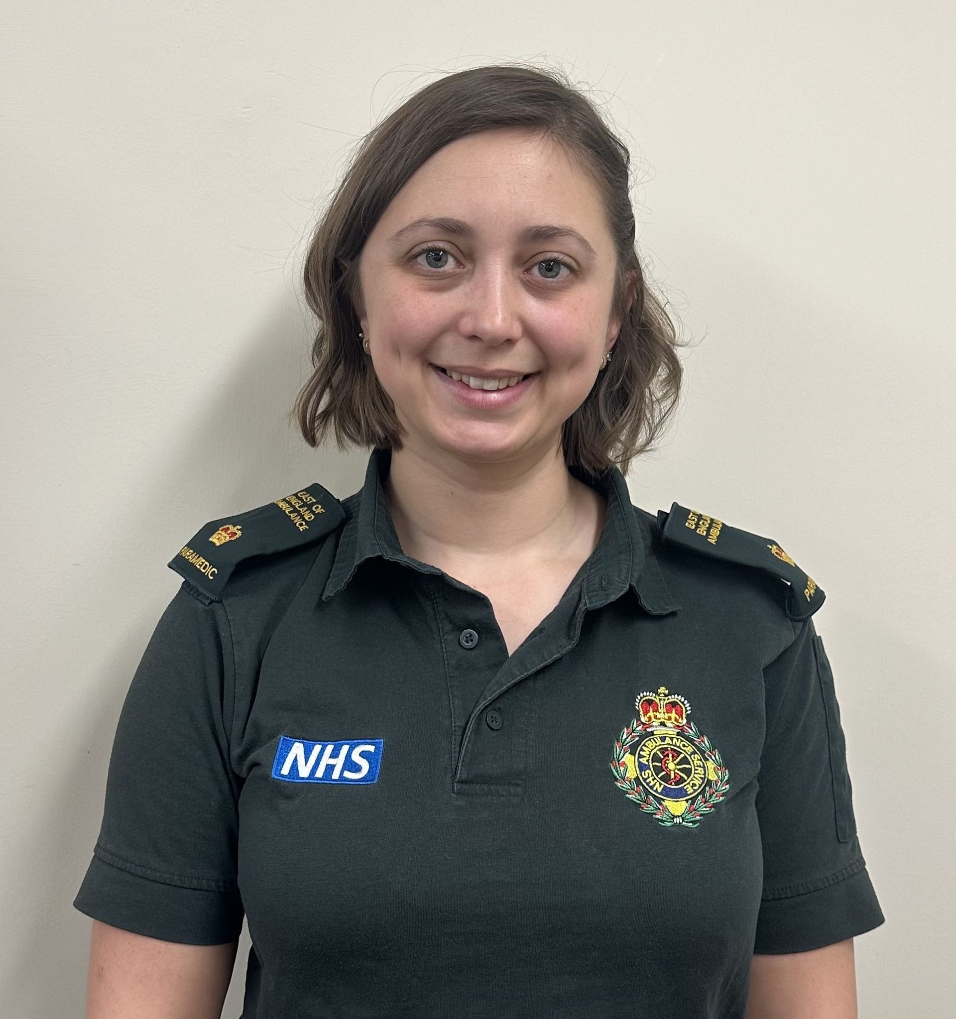 A photo of Jess who has short brown hair in ambulance uniform.