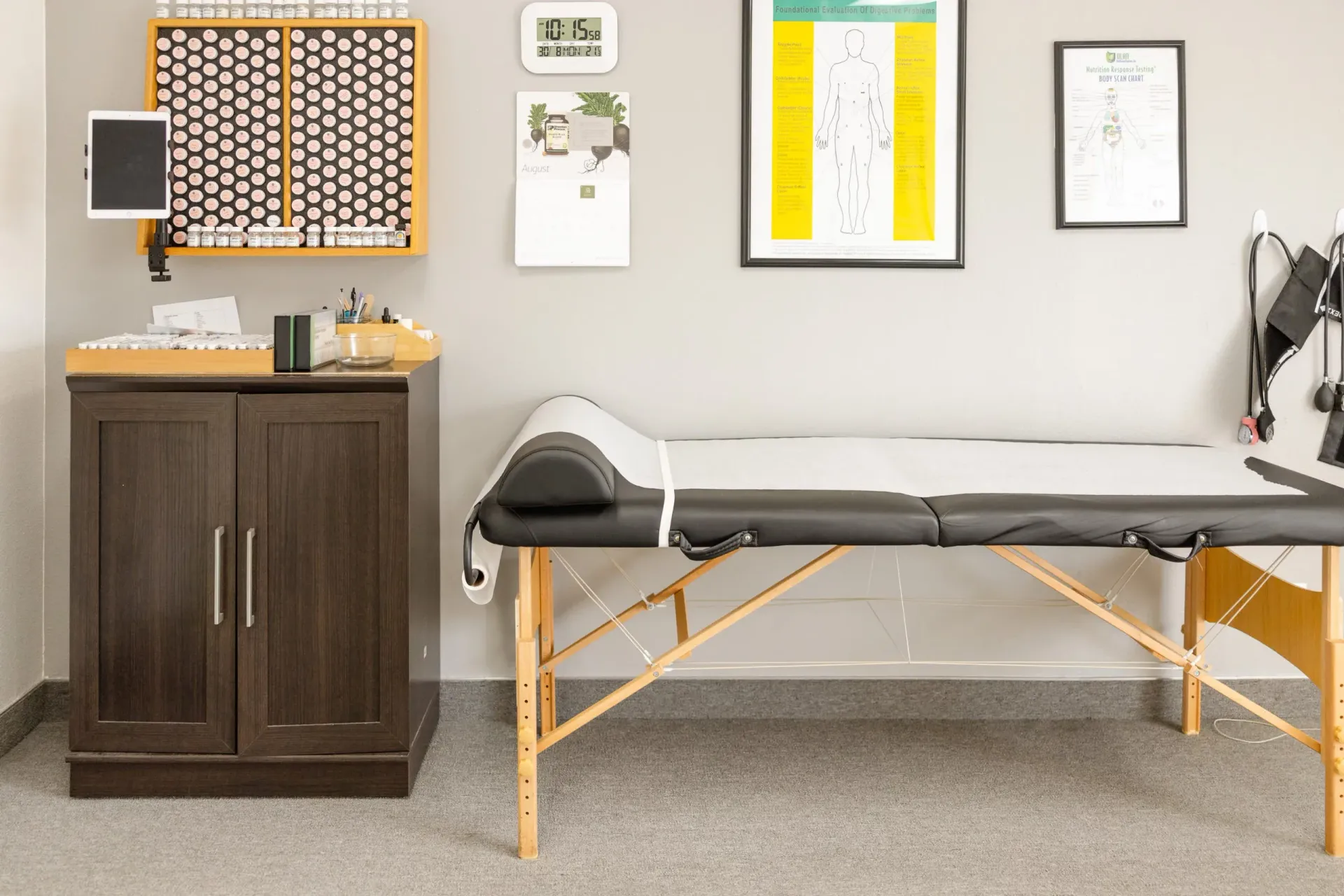 A physical therapy room with a massage table, cabinet, and wall-mounted tools.