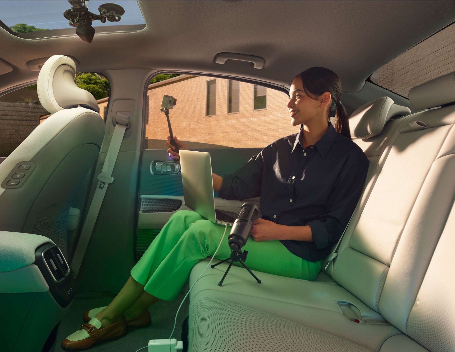 A woman is sitting in the back seat of a car using a laptop. Ioniq 6