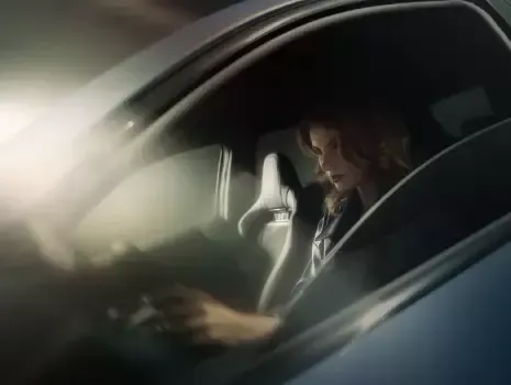 A woman is sitting in the driver 's seat of a car. Ioniq 5