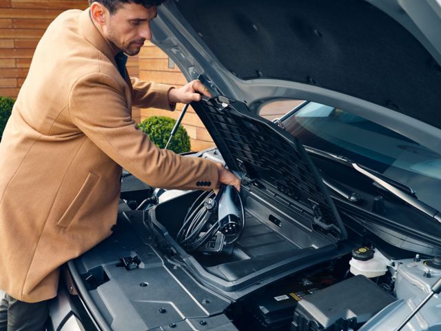 A man is looking under the hood of a car. ioniq 5