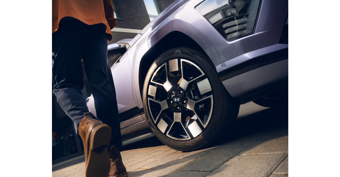 A person is walking towards a purple car. Kona Electric