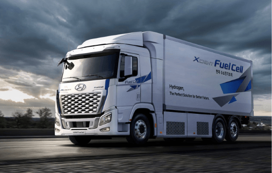 A hyundai fuel cell truck is driving down a road.