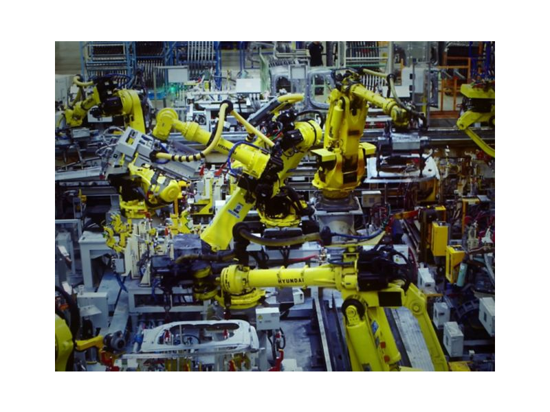 A bunch of yellow robots are working in a factory.