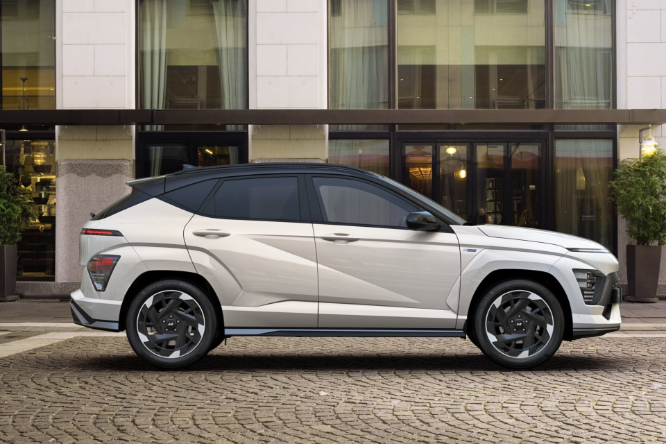 A white suv is parked in front of a building on a cobblestone street. Kona N Line Electric