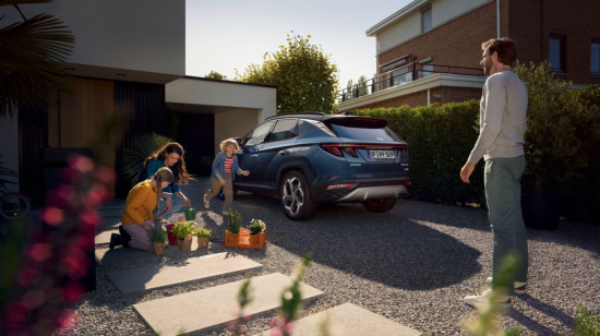A family is planting flowers in front of a blue car. Tucson