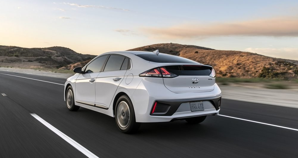 A white hyundai ioniq is driving down a desert road.