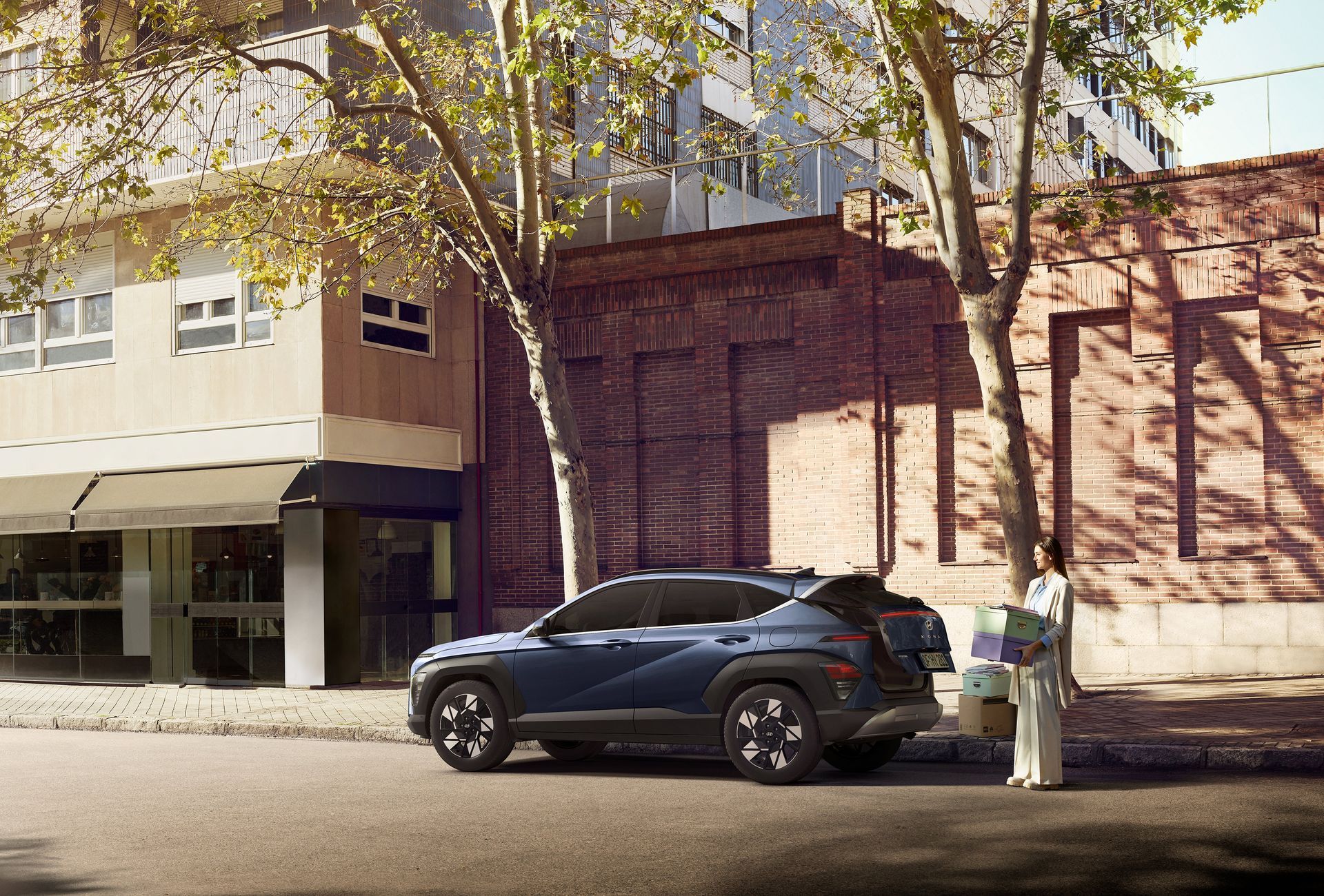 A blue suv is parked on the side of the road in front of a building. Kona