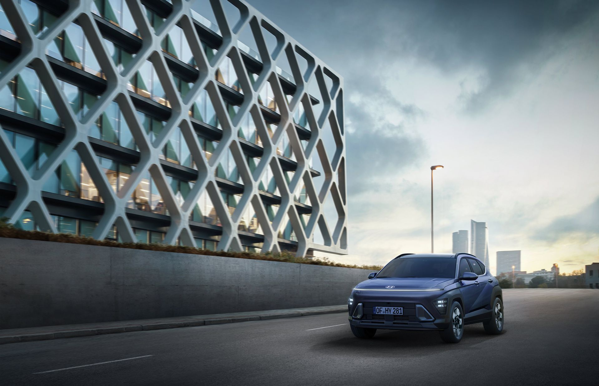 A blue car is parked on the side of the road in front of a building. Kona