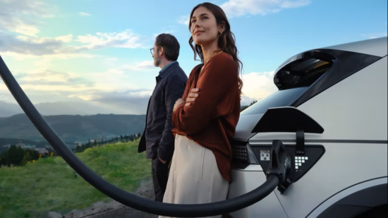 A man and a woman are standing next to a car that is being charged. Ioniq 5