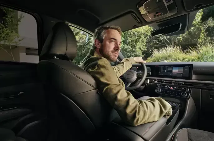 A man is sitting in the driver 's seat of a car.