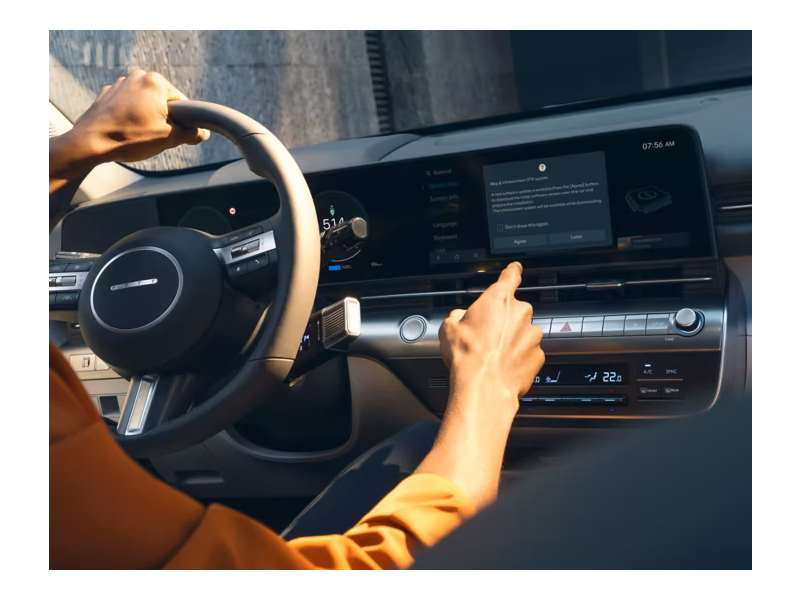 A person is driving a car and pressing a button on the dashboard. Kona Electric