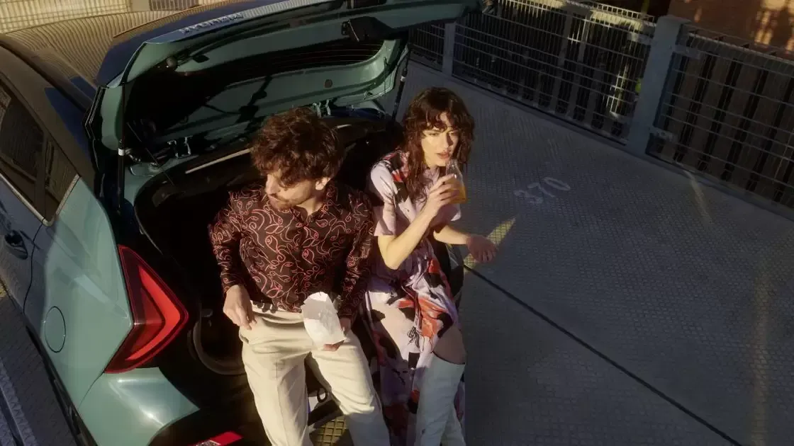 A man and a woman are standing in the back of a car.