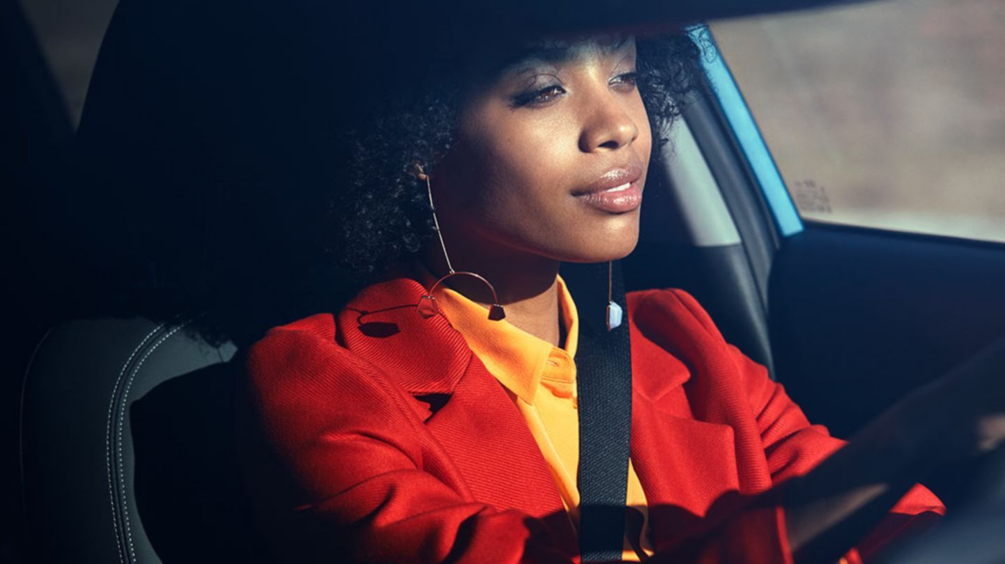 A woman in a red jacket is driving a car.